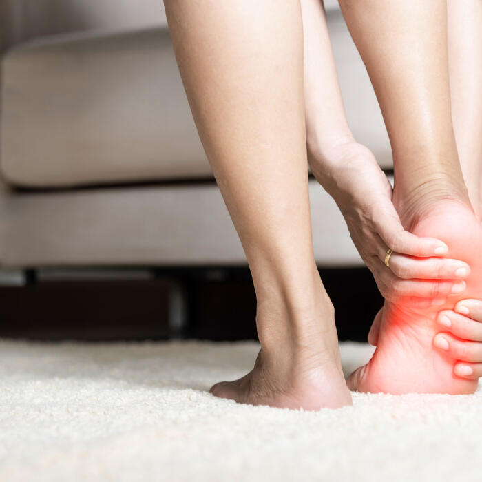 Woman gripping her painful ankle with red inflammation highlight on the joint